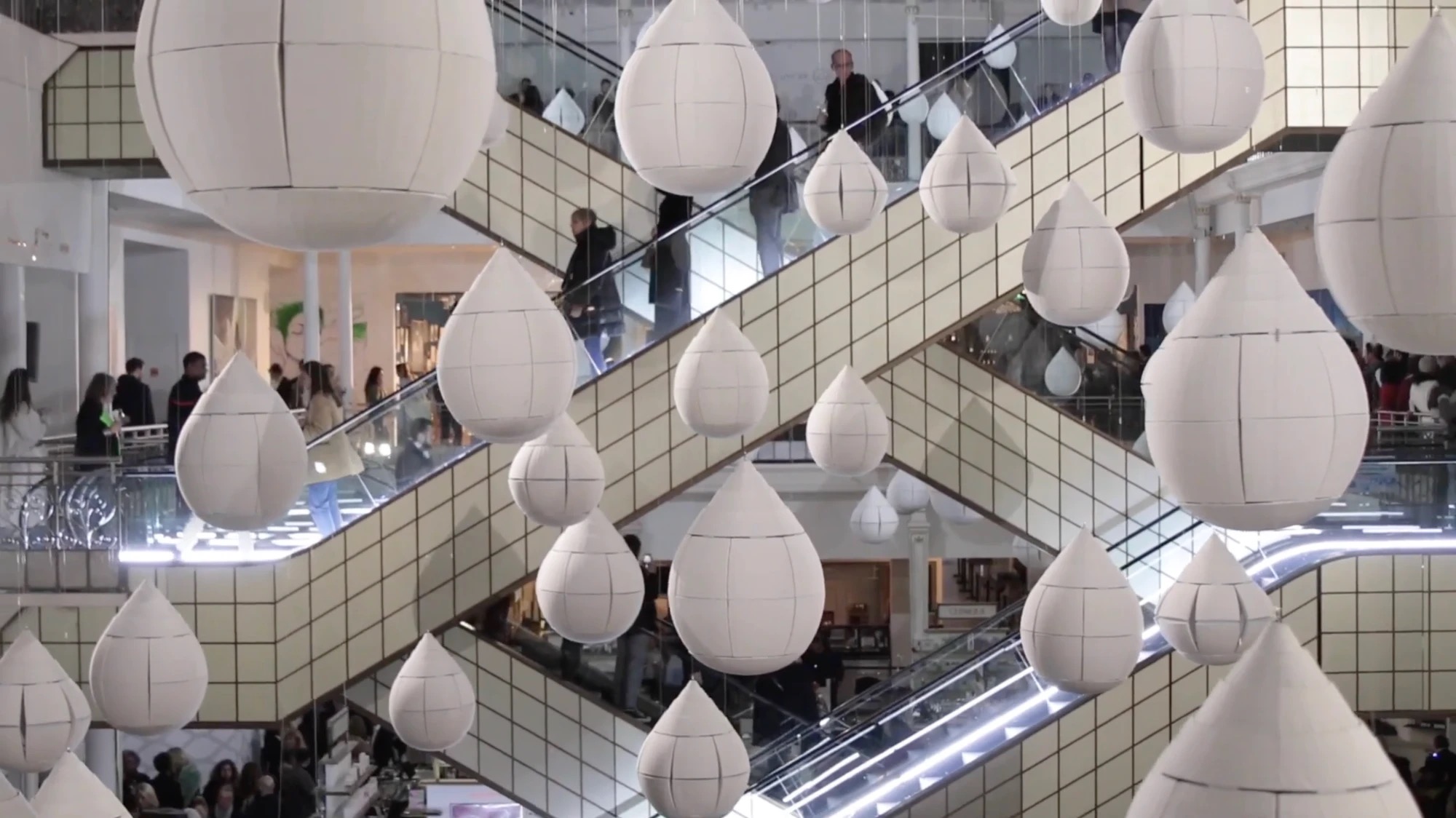 Gouttes de pluie géantes en papier suspendues dans l'atrium du Bon Marché, installation "Ame Nochi Hana" d'Oki Sato
