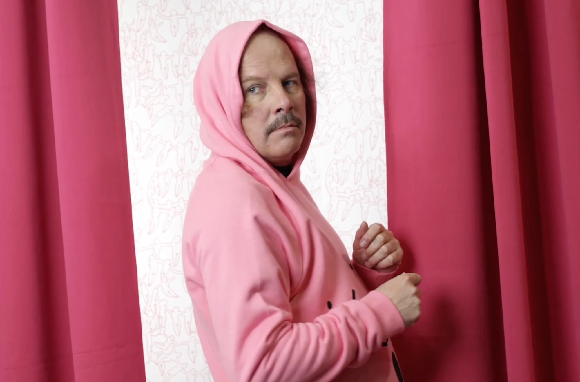 Philippe Katerine en sweat rose, devant le décor du Mignonisme au Bon Marché Rive Gauche