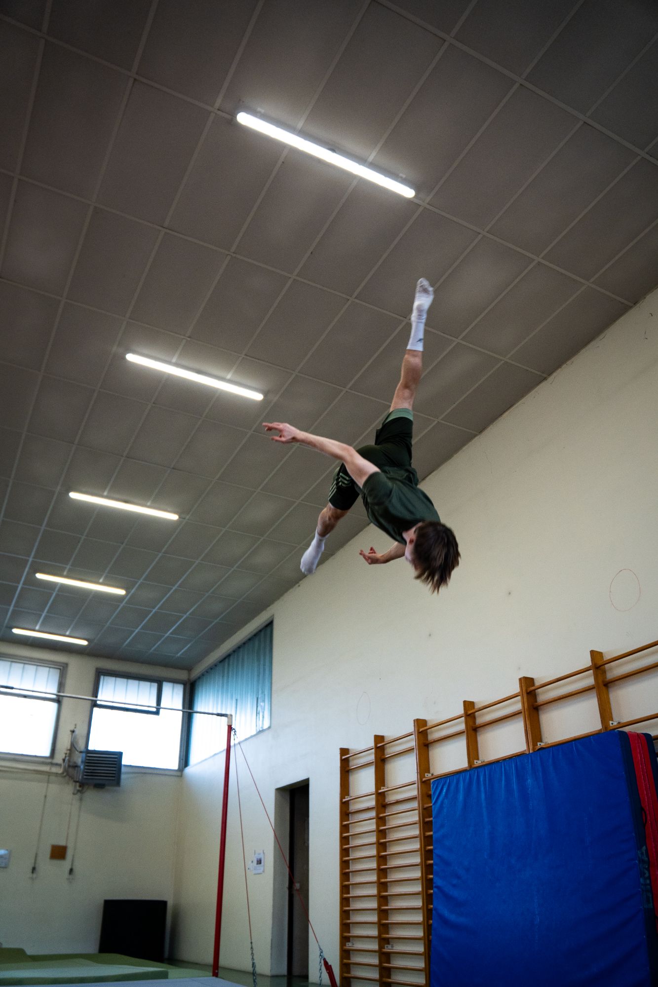 Gymnaste en pleine figure acrobatique, tête en bas, dans un gymnase